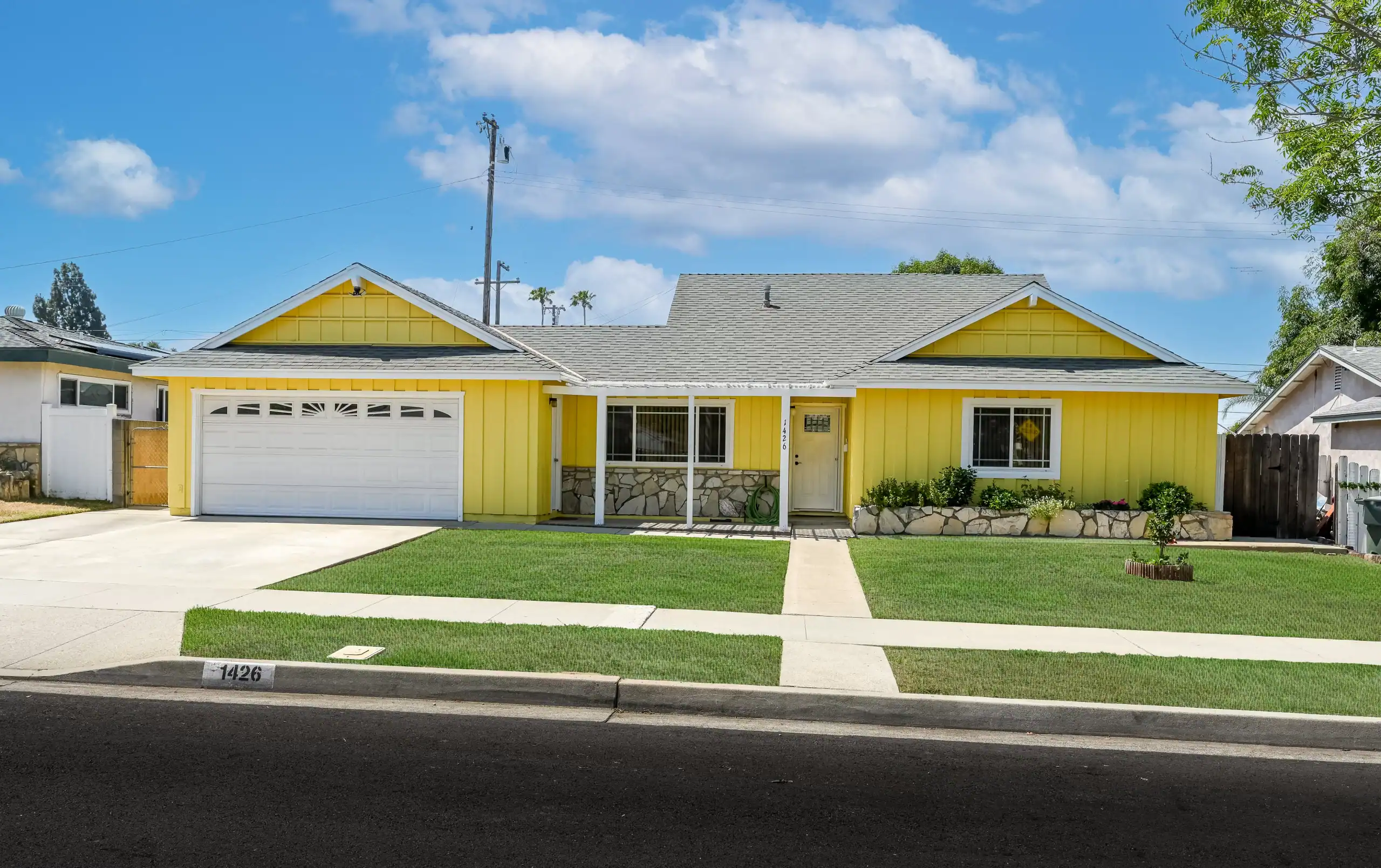 Widlomar real estate photography of a yellow house with a garage and a driveway.